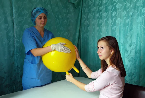 Врач и пациент в руках массируют желтый надувной шар — стоковое фото