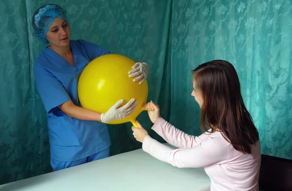 Physician and patient in their hands massaging yellow inflatable ball — Stock Photo, Image