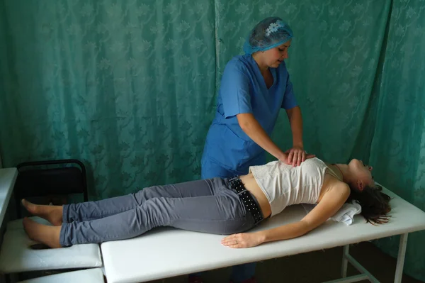 El paciente yace inconsciente sobre una mesa, el médico hace un masaje al corazón Imagen de archivo