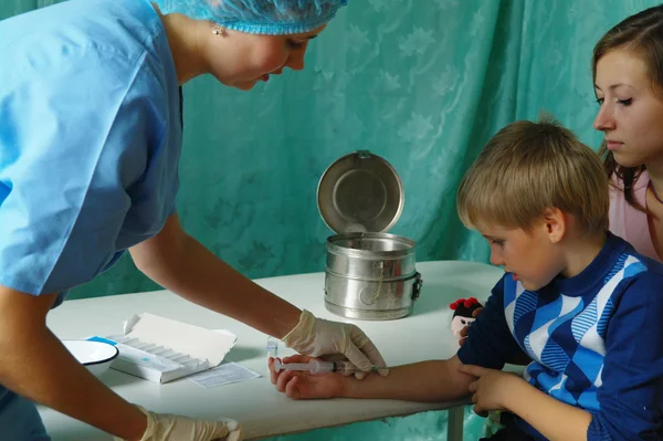 Un médico de la clínica hace que la jeringa para inyección sea para niños Imagen de archivo