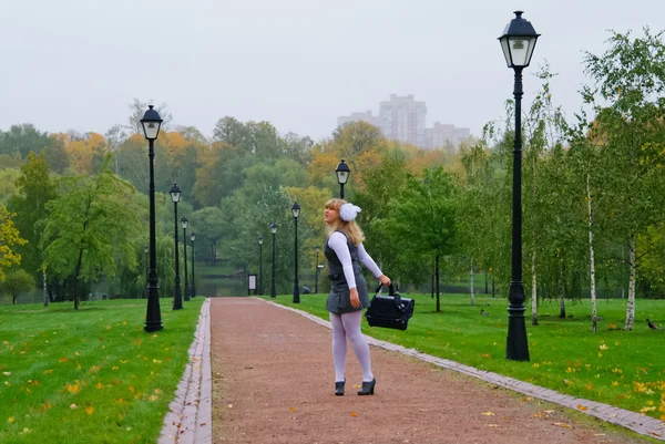 The schoolgirl walking down the avenue autumn park — Stock Photo, Image