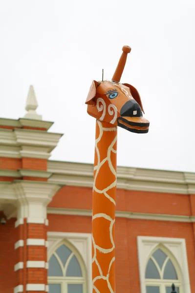Cabeza de jirafa de madera contra el edificio, parque — Foto de Stock