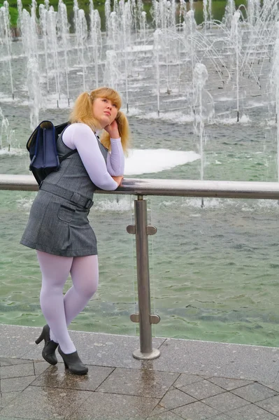 A estudante de pé perto da fonte com uma pasta — Fotografia de Stock