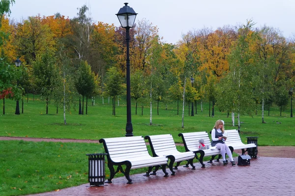 La colegiala sentada en un banco en Autumn Park — Foto de Stock
