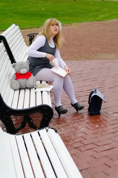 Школярка, сидячи на лавці в Осінній Парк — стокове фото
