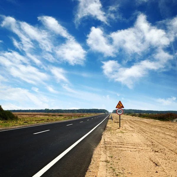 Largo camino de asfalto y cielo azul — Foto de Stock