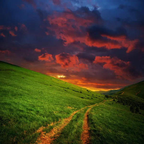 Heuvels en weg naar rood wolken — Stockfoto