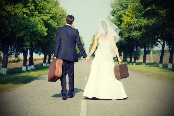 Couple holding suitcases on road — Stock Photo, Image