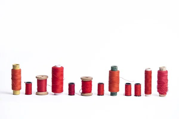 Different bobbins with red-colored sewing strings — Stock Photo, Image