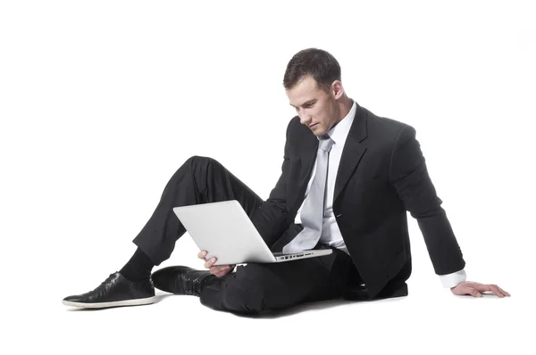 Stilig ung affärsman som sitter med den bärbara datorn Stockfoto