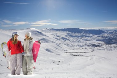 Two happy snowboarders in snow covered mountains clipart