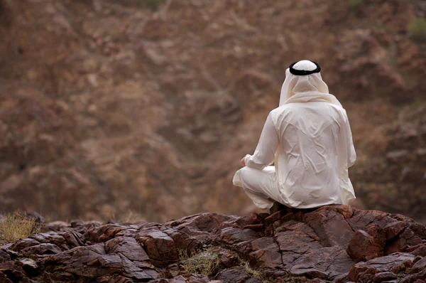 Hombre árabe sentado en las rocas — Foto de Stock