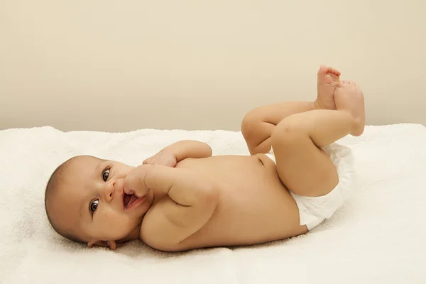 Новорожденный ребенок в подгузнике улыбается — стоковое фото