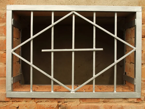 Metallgitter im Fenster eine Ziegelwand — Stockfoto