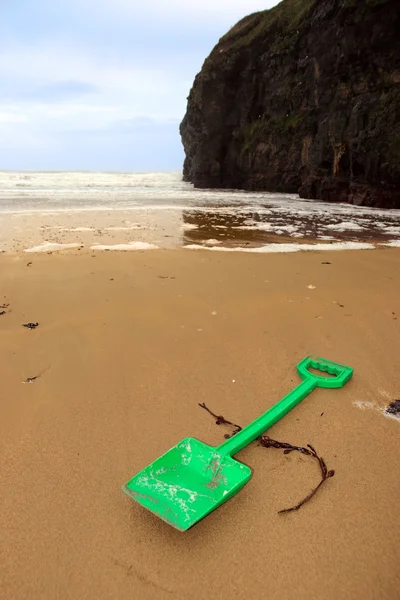 Plastic green spade on golden beach — Stock Photo, Image
