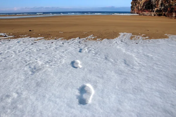 Footprints in snow on empty beach on a cold winters day — Stock Photo, Image