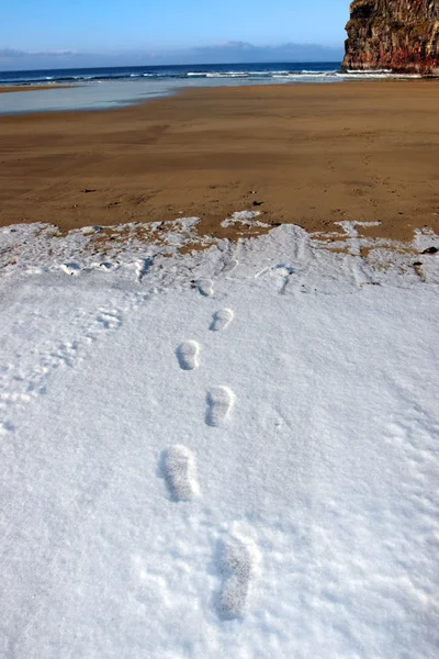 Κομμάτια αποτύπωμα στο χιόνι στις άδειο παραλία για μια ημέρα κρύους χειμώνες — Φωτογραφία Αρχείου