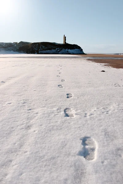 Fotspår i snön på tom strand med slottet — Stockfoto