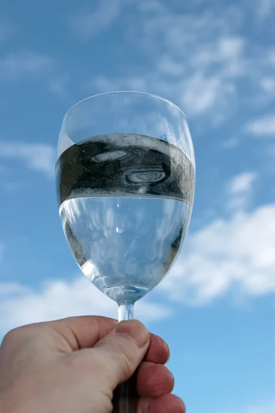 Un vaso de agua contra un brindis azul — Foto de Stock