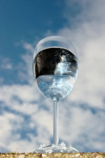 Bicchiere d'acqua contro un cielo blu — Foto Stock