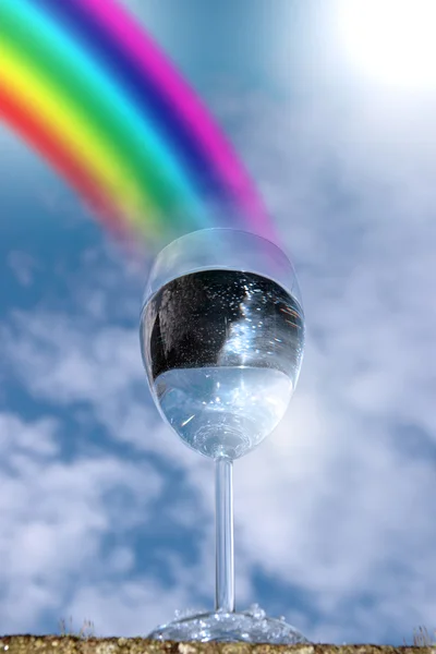Un vaso de agua contra un cielo soleado con arco iris —  Fotos de Stock