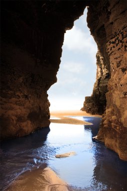 Inside golden beach cliff cave clipart