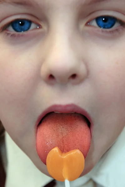 stock image Blue eyed girl licking an orange lollipop