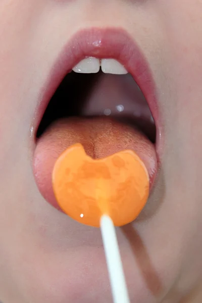 stock image Girl licking an orange lollipop