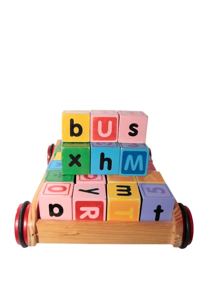 Childrens play blocks spelling bus in wooden cart isolated on wh — Stock Photo, Image