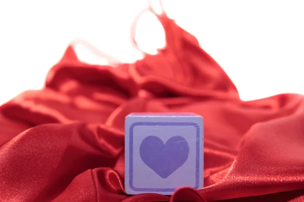 Игрушечное пурпурное любовное сердце на шелковой ночнушке — стоковое фото
