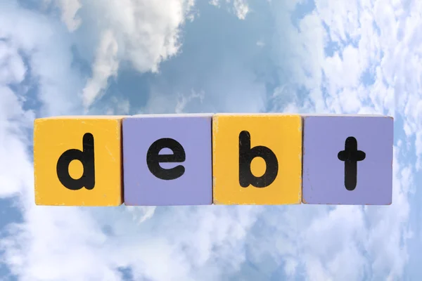 Dívida em brinquedo jogar letras de bloco com recorte caminho em nuvens — Fotografia de Stock