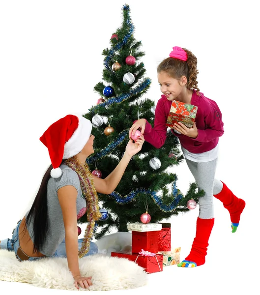 Mother and daughter near a christmas tree with gifts, isolated on a white b Stock Photo