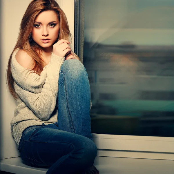Belle fille aux cheveux longs, assise sur un rebord de fenêtre — Photo