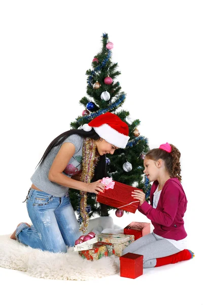 Madre e hija cerca de un árbol de navidad con regalos, aisladas en una b blanca — Foto de Stock