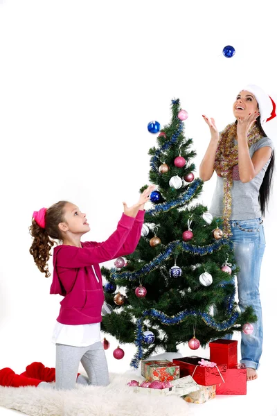 Mother and daughter near a christmas tree with gifts, isolated on a white b — Stock Photo, Image