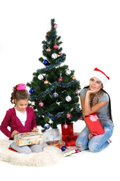 Mãe e filha perto de uma árvore de Natal com presentes, isolado em um b branco — Fotografia de Stock