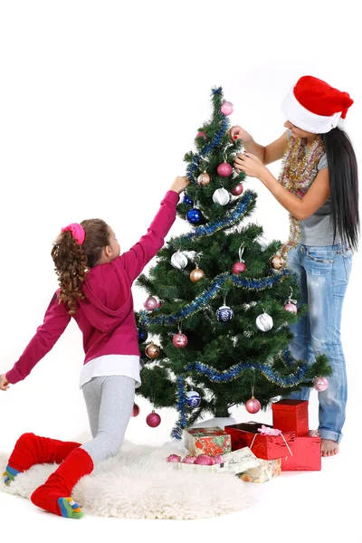 Mãe e filha perto de uma árvore de Natal com presentes, isolado em um b branco — Fotografia de Stock