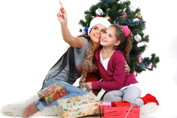 Madre e figlia vicino a un albero di Natale con doni, isolati su una b bianca — Foto Stock