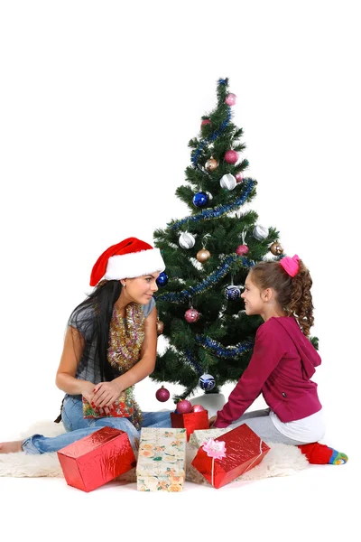 Matka a dcera v blízkosti vánoční stromeček s dárky, izolovaných na bílém b — Stock fotografie