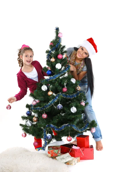 Mother and daughter near a christmas tree with gifts, isolated on a white b Royalty Free Stock Images