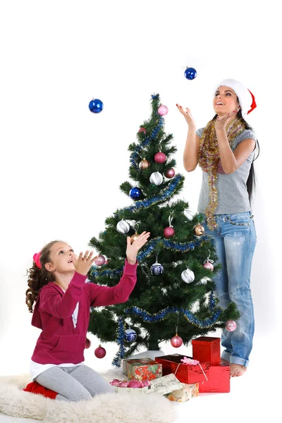 Mother and daughter near a christmas tree with gifts, isolated on a white b — Stock Photo, Image