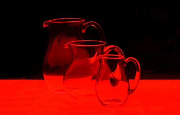 Trzy dzbanki szklane w czerwone światło — Zdjęcie stockowe