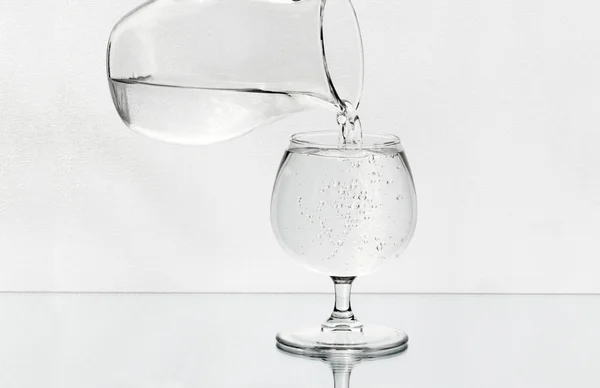 ワイングラスは、ガラスの水差しから水でいっぱいです。 — ストック写真