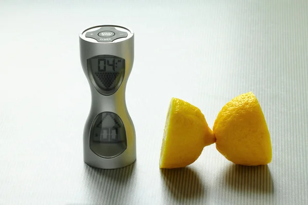 Un reloj y dos trozos de limón sobre la mesa — Foto de Stock