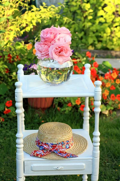 Roze rozen en een stro zomer hoed — Stockfoto