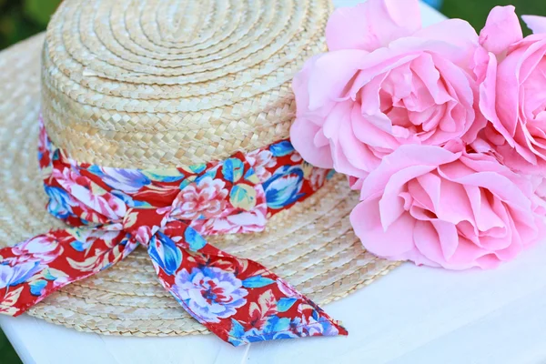 Precioso sombrero de paja de verano y rosas rosadas — Foto de Stock