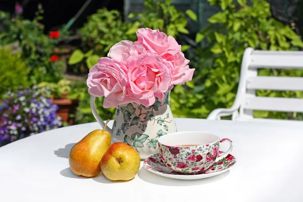 Lovey sommarträdgård med rosa rosor och päron på vitt bord — Stockfoto