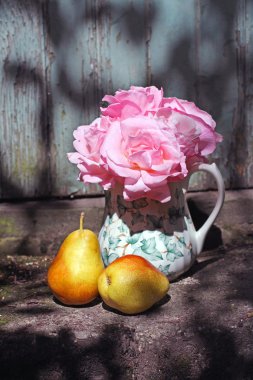 Beautiful vase with pink roses and pears in the garden clipart