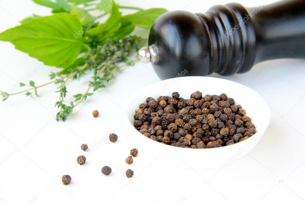 Black pepper in a bowl and herbs