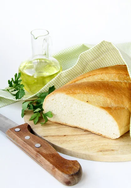 Fresh white loaf of bread with a knife , olive oil , rustic style — Stock Photo, Image